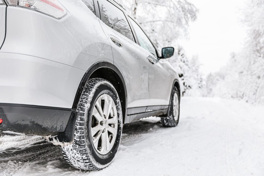 Car tire on a winter road in snow covered forest.