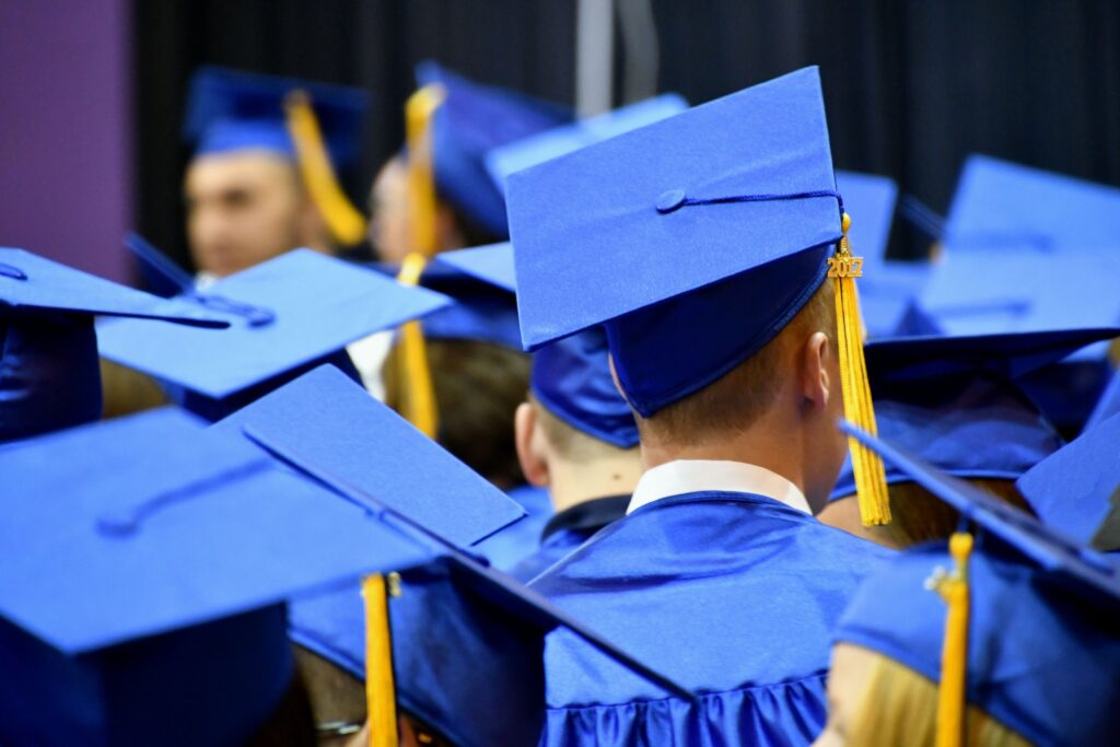 A male graduate in the midst of a group of graduates at a graduation ceremony.