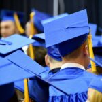 A male graduate in the midst of a group of graduates at a graduation ceremony.