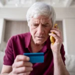 worried senior man on a phone looking at a credit card avoid scam calls